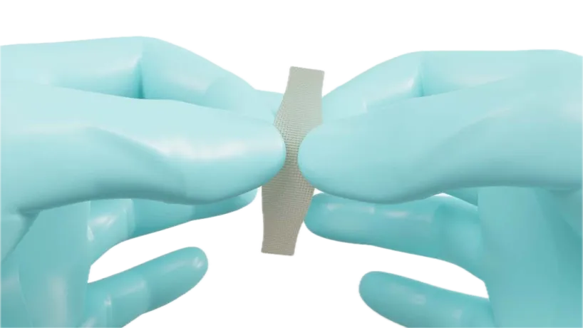 Dentapreg® VEIL strip held between two gloved hands, showcasing its flexibility and lightweight design, ideal for dental reinforcement applications.